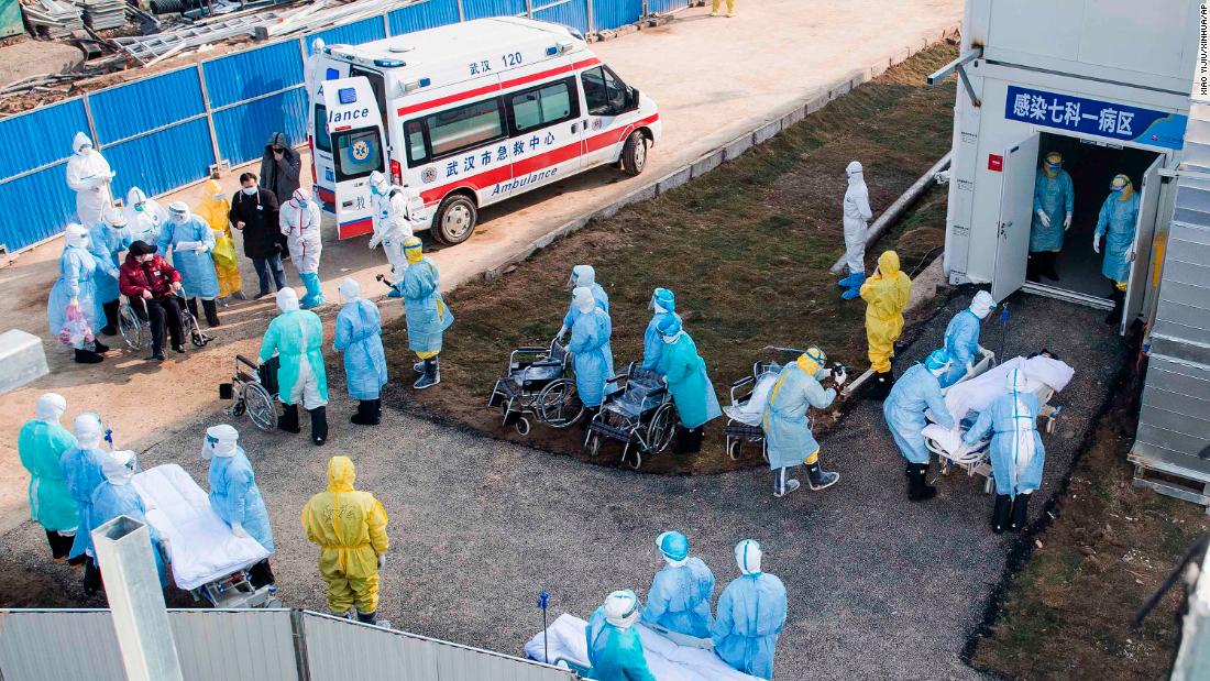 Medical workers in protective suits help transfer patients to a newly completed field hospital in Wuhan.